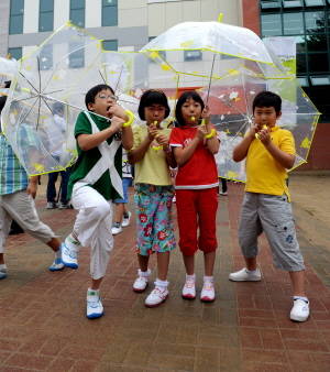 현대모비스가 제작·배포하는 투명우산을 전달받은 초등학생들이 우산에 달린 호루라기를 불어보고 있다. ⓒ 현대모비스
