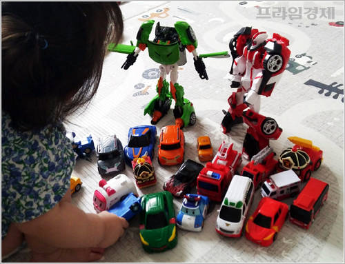 오빠가 없는 사이 장난감 만져보는 둘째. 그나마 멀쩡한 아이들만 뽑아 찍었고 뒤에 커다란 소쿠리 두 개에 미니카 장난감이 한 가득 들어있다. = 이수영 기자