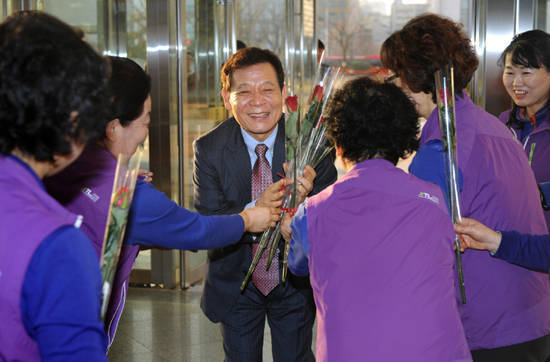 2015년 새해 첫 결재로 '공공부문 비정규직 고용개선 대책'에 서명한 윤장현 광주시장이 1월6일 오전 출근길에 꽃을 받고 있다. 이날 시청사 청소용역근로자 30여명이 장미꽃 한 송이씩을 손에 들고, 1층 시민홀 입구에서 윤 시장을 맞았다. ⓒ 광주시청