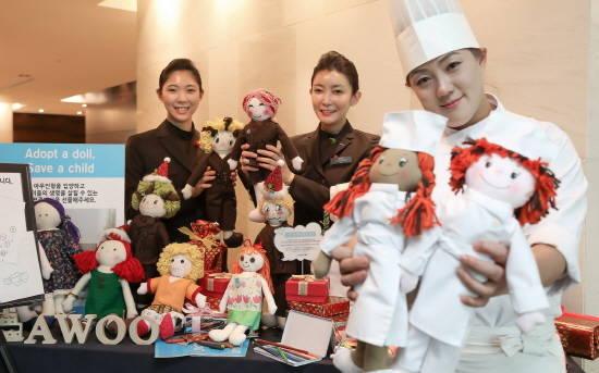 부산롯데호텔 직원들이 22일 호텔 33층 클럽라운지에 마련된 아우인형 전시장에서 같은 유니폼을 입은 아우인형을 들고 밝게 웃고 있다. ⓒ ㈜부산롯데호텔