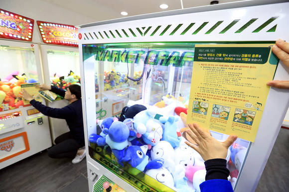 지난 3월20일 광주 북구 전남대 인근 한 인형뽑기방에서 구청 문화관광과 영상음반팀 직원들이 경품 종류 위반과 영업자 준수사항 위반시 처벌 홍보전단지를 부착하고 있다.(광주 북구청 제공) ⓒ 뉴스1