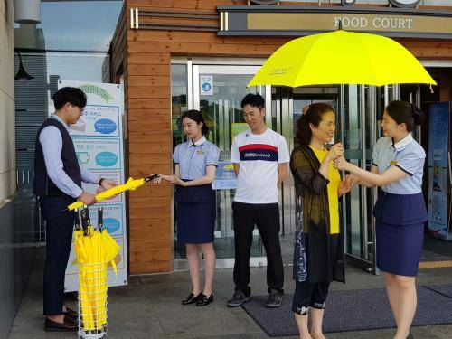 휴게소 직원들이 갑자기 비가 내려 우산이 없는 고객에게 우산을 씌어주고 있다. ⓒ 풀무원푸드앤컬처