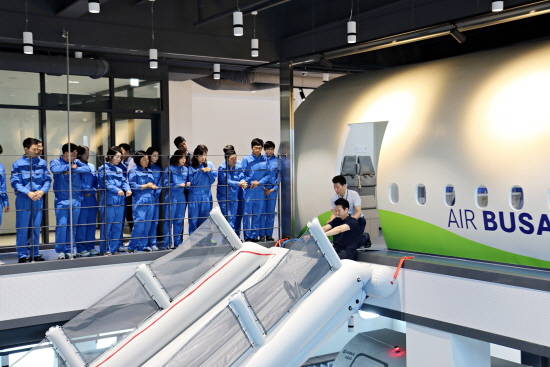 안전대회의 과정 중 각 부서별 안전 담당자와 신규 입사자들이 비상탈출 슬라이드 체험에 앞서 교관의 설명을 듣고 있다. ⓒ 에어부산