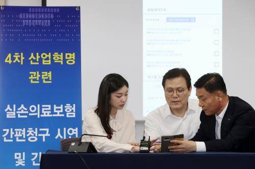 최종구 금융위원장과 김연아가 4차 산업혁명 기술이 접목된 실손의료보험 간편청구 시연에 참여하고 있다. 최 위원장은 향후 실손의료보험금 청구 방식을 금융소비자가 휴대전화 앱을 활용, 원스톱으로 보험 청구를 하거나 병원이 보험사로 의료 정보를 직접 보내는 방식으로 개편하겠다고 밝혔다. ⓒ 뉴스1