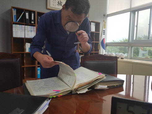 오래된 행정현안 수첩들을 살펴보는 오규석 군수. 에어컨을 틀지 않아 창문을 열어놓은 것이 뒤로 보인다. ⓒ 프라임경제