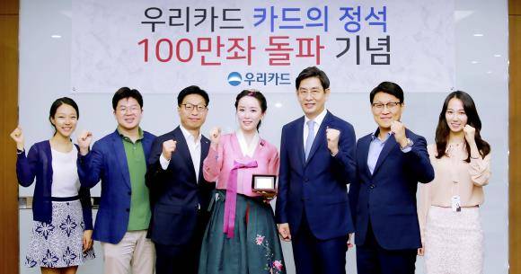 30일 우리카드 본사에서 진행된 '카드의정석' 100만좌 돌파 기념식에서 정원재 우리카드 사장(왼쪽에서 다섯 번째)이 김현정 한국화가에게 감사의 표시로 기념카드를 전달하고 상품개발에 참여한 유공직원 5명과 함께 기념 촬영하고 있다. ⓒ 우리카드