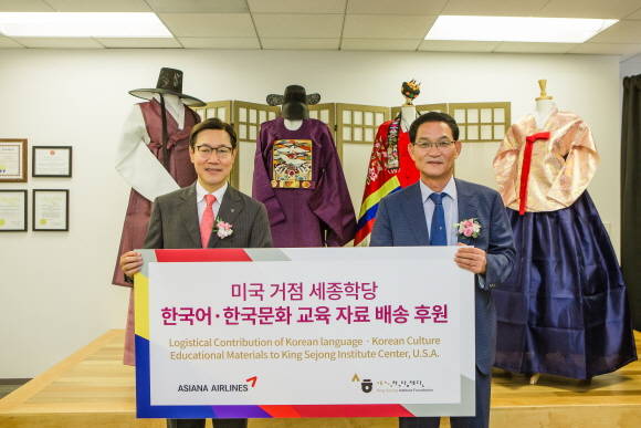 미국 거점 세종학당 개원식에 참석한 김영헌 아시아나항공 미주지역본부장(왼쪽)과 권오기 세종학당재단 이사장 직무대행이 한국어 교육자료를 전달하며 기념촬영을 하고 있다. ⓒ 아시아나항공