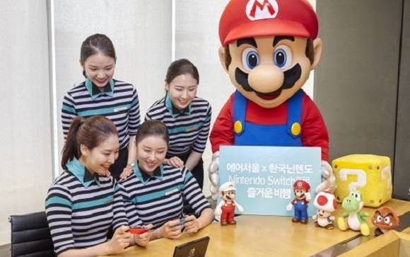 에어서울 비행기 안에서 안내를 해주는 승무원과 슈퍼 마리오 인형을 입은 사람이 기념사진을 찍은 모습이에요. ⓒ 에어서울