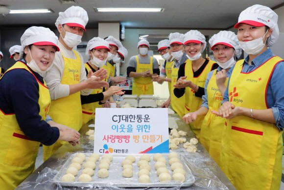 CJ대한통운 임직원들과 관계자들이 이웃들을 위해 정성스럽게 빵을 만들며 기념촬영을 하고 있다. ⓒ CJ대한통운
