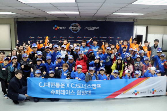 CJ대한통운 임직원, CJ도너스캠프 대학생봉사단, 초월초등학교 학생들이 CJ로지스틱스 레이싱팀 선수들과 함께 기념촬영을 하고 있다. ⓒ CJ대한통운