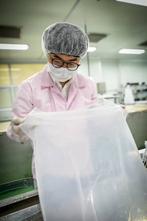 SK 바이오랜드 직원이 미생물로 만든 바이오셀루로스 마스크팩 시트 원단을 살펴보고 있다. ⓒ SKC