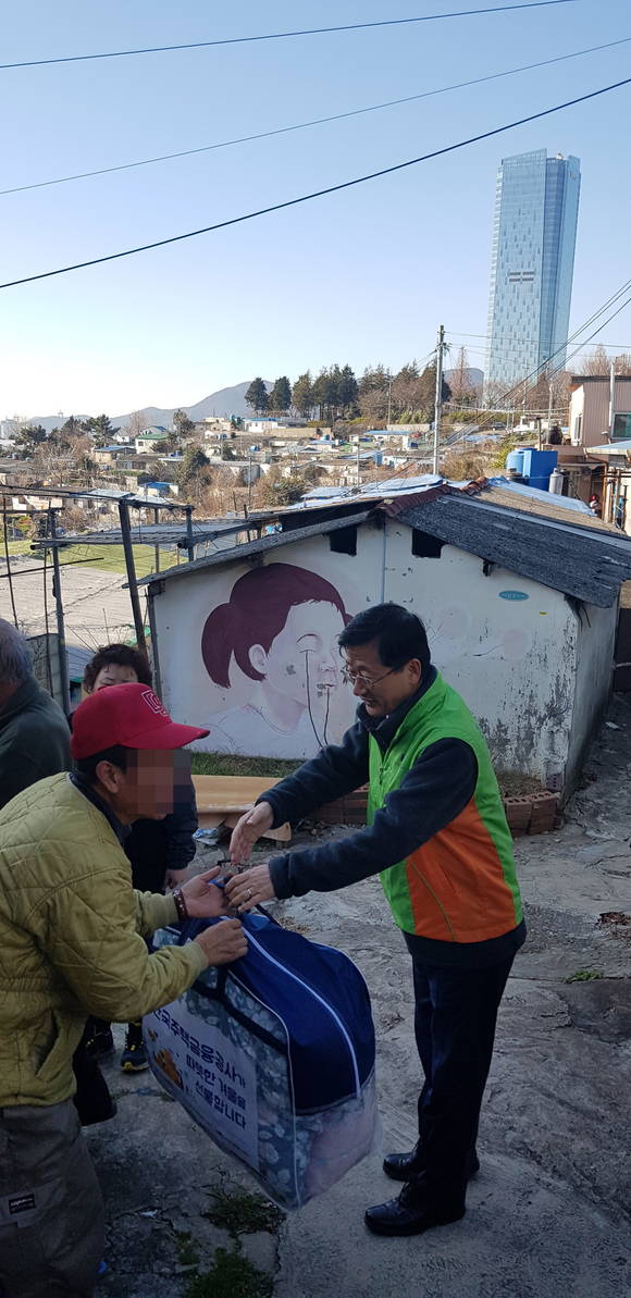 부산 남구 벽화마을 주민에게 이불이 든 가방을 전달하는 이정환 사장. ⓒ 프라임경제