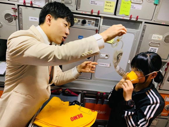 제주항공 객실승무원이 기내에서 어린이 탑승객들을 대상으로 비상상황 발생시 산소마스크 및 구명복 착용방법을 가르쳐 주고 있다. ⓒ 제주항공