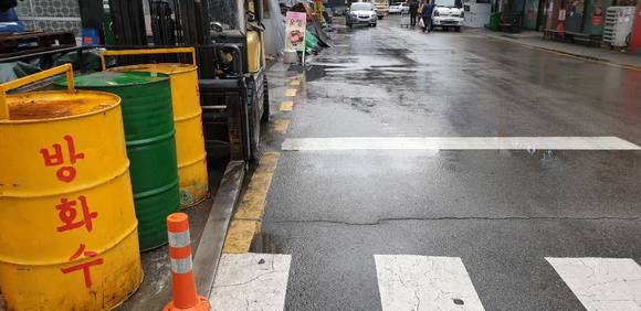 부산 진구 전포동에 위치한 '자동차부품상가' 보행로에 쌓인 불법 적치물로 인해 주민들이 통행에 많은 불편을 겪고 있다. ⓒ 프라임경제