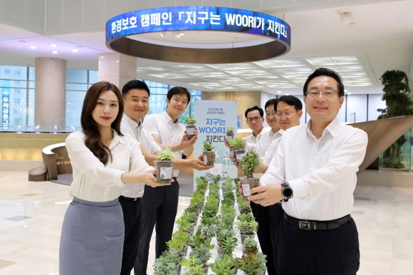 손태승(사진 우측) 우리금융그룹 회장이 지난 22일 임원진과 함께 본점 로비에서 플라스틱 컵을 재활용한 화분을 출근길 직원에게 나눠주는 행사를 가졌다. Ⓒ 우리은행