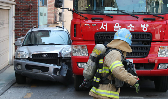 지난해 서울 종로구 필운대로 주택가에서 서울시 소방재난본부 소속 소방관들이 소방활동 방해 주차 차량 강제처분 훈련을 하며, 통행로를 막은 불법주차 차량을 소방차로 파손하며 출동하는 연습을 하고 있다. ⓒ 연합뉴스