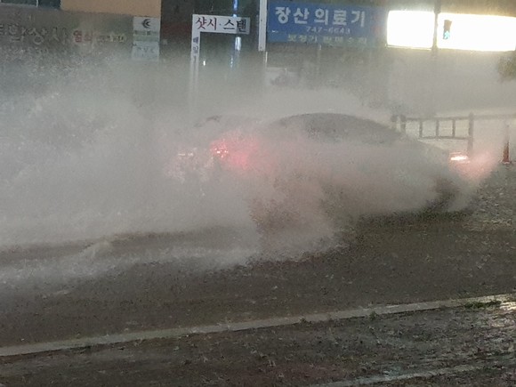 23일 시간당 80mm가 넘는 장대비로 인해 부산 해운대구 중2동 달맞이 입구 도로가 쏟아져 흘러오는 빗물로 급류를 이뤄 이곳을 지나가는 차량들을 위협하고 있다. = 서경수 기자