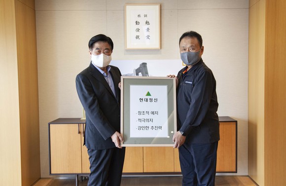 권오갑 현대중공업지주 회장(왼쪽)이 손동연 두산인프라코어 사장에게 정주영 창업자의 경영 철학이 담긴 '현대정신' 액자를 전달하고 있다. ⓒ 현대중공업