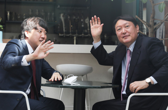 국민의힘 이준석 대표(왼쪽)와 윤석열 대선 후보가 이달 6일 오후 서울 마포구 한 음식점에서 오찬 회동 중 창밖에 모인 시민들을 향해 손을 흔들고 있다. ⓒ 연합뉴스