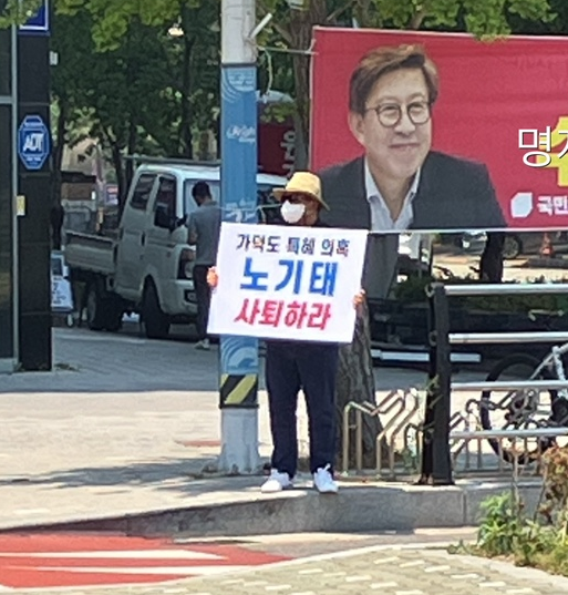 부산 강서구 한 대로변에서 신원을 알 수 없는 사람이 노기태 후보를 비판하는 글귀가 써 진 피켓을 들고 서 있다. ⓒ 제보자