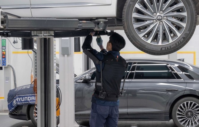 현대차 고양하이테크센터에서 작업자가 '엑스블 숄더'를 착용하고 차량 하부를 정비하는 모습. ⓒ 현대자동차