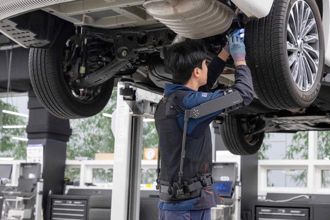 현대차 고양하이테크센터에서 작업자가 '엑스블 숄더'를 착용하고 차량 하부를 정비하는 모습. ⓒ 현대자동차