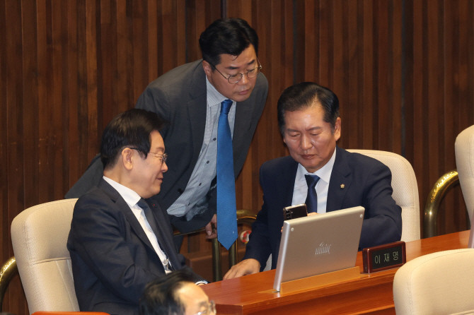 이재명 대통령(당시 더불어민주당 대표)과 박찬대 민주당 전 원내대표(가운데), 정청래 민주당 의원(오른쪽)이 작년 9월 대정부 질문이 진행된 국회 본회의장에서 휴대전화를 함께 보며 대화하고 있다. ⓒ 연합뉴스