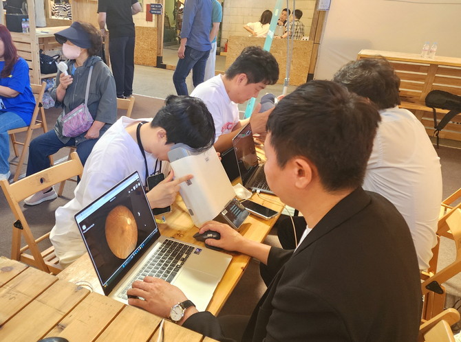 대웅제약 부스 방문객이 위스키와 옵티나를 활용해 안저 상태를 확인하고 있다. © 대웅제약