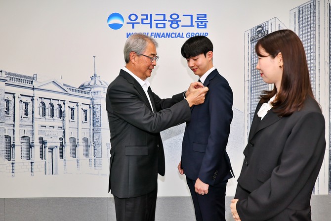임종룡 우리금융 회장이 그룹의 새 가족이 된 동양생명·ABL생명 직원에게 디지털 선도의 의미가 담긴 새로운 그룹 보조휘장을 달아주고 있다. ⓒ 우리금융그룹