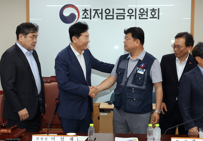 최저임금위원회 사용자위원 운영위원인 류기정 한국경영자총협회 전무(왼쪽)와 근로자위원 운영위원인 류기섭 한국노총 사무총장이 10일 정부세종청사에서 열린 제12차 전원회의에서 내년 최저임금을 시간당 1만320원으로 17년 만에 합의로 결정한 뒤 악수하고 있다 ⓒ 연합뉴스