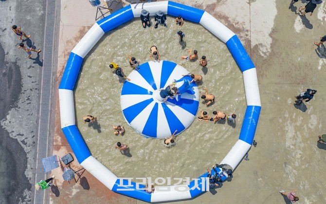 2025 보령머드축제 체험존에서 참가자들이 원형 풀장 안에서 중앙의 파란색과 흰색으로 꾸며진 대형 에어 구조물 위에서는 어린이들이 뛰놀고 있다. ⓒ 프라임경제