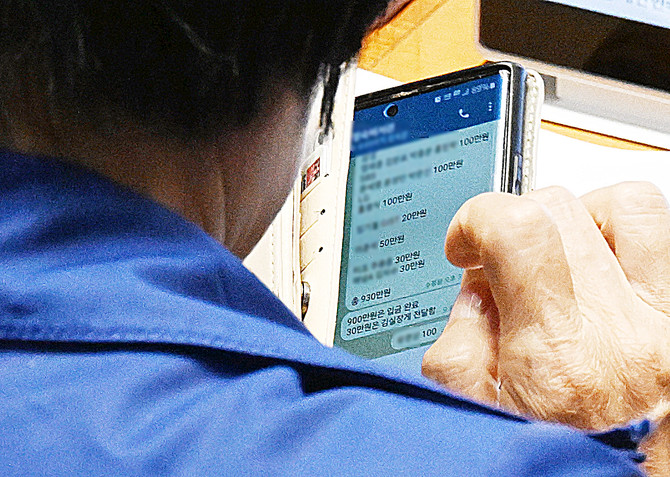 국정감사 기간 딸 결혼식으로 논란을 빚은 국회 과학기술정보방송통신위원장인 더불어민주당 최민희 의원이 지난 26일 국회 본회의장에서 축의금과 관련한 텔레그램 메시지를 보고 있다. 대기업, 언론사 이름과 금액이 적혀 있는 이 메시지는 최 위원장이 축의금을 돌려주는 과정 중 보좌진과 주고받은 내용으로 추정된다. © 연합뉴스