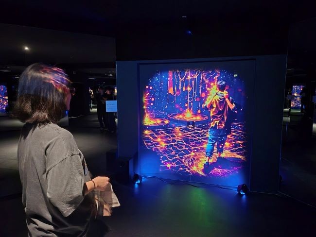 AR그래픽과 실내 조명이 어우러진 '용화향도 시즌2' 체험 공간에서 방문객이 몰입형 전시를 즐기고 있다. ⓒ 경주시