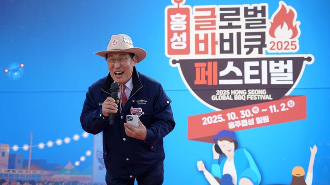 2025 홍성글로벌바비큐페스티벌을 홍보하기 위해 포즈를 취한 이용록 군수가 배경 패널 앞에서 활짝 웃으며 축제 분위기를 강조하고 있다. ⓒ 홍성군