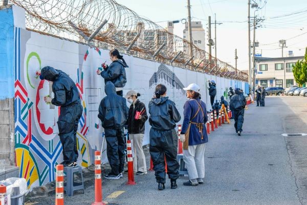 벽화 그리기 활동에 참여한 장병과 군 가족들이 밑그림에 채색을 하고 있다. ⓒ 공군 제1전투비행단