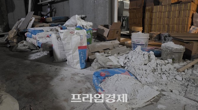 아파트 지하주차장의 한 공간에 시멘트가 담긴 포대, 타일 조각, 판자, 골판지 상자 등이 무질서하게 쌓여 있다. ⓒ 프라임경제