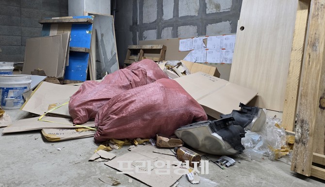 아파트 지하주차장의 한 공간에 시멘트가 담긴 포대, 판자, 골판지 상자 등이 무질서하게 쌓여 있다. ⓒ 프라임경제