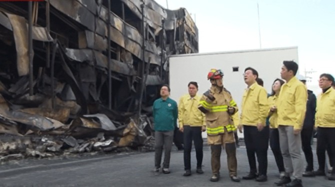 이재명 대통령이 지난 21일 14명이 사망하고 60명이 중경상을 입은 대전시 대덕구 문평동 자동차부품제조공장 화재 현장을 찾아 현장을 점검하고 있다. ⓒ YTN뉴스 캡처