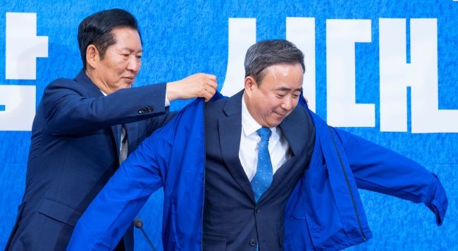 임문영 AI전략위원회 상근부위원장이 6일 국회에서 열린 더불어민주당 인재 영입식에서 정청래 대표에게 파란 점퍼를 전달받은 뒤 입고 있다. ⓒ 연합뉴스