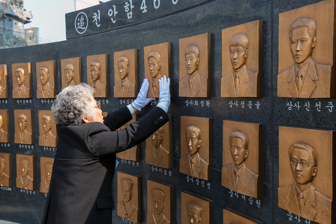 천안함 46용사 추모 공간에 새겨진 전사 장병들의 얼굴. 한 유가족이 부조를 어루만지고 있다. ⓒ 국방일보