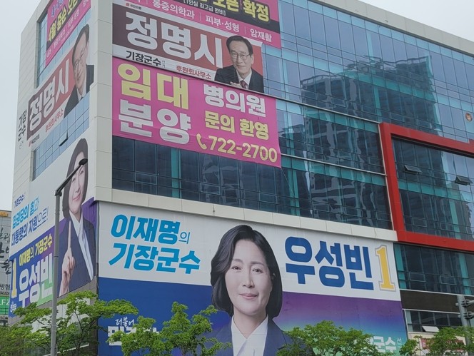 6·3 전국동시지방선거를 앞두고 부산 기장군 일광신도시 일원 한 상가 건물에 이번 기장군수 선거에 출마한 민주당 우성빈 후보와 국민의힘 정명시 후보의 선거 홍보현수막이 위 아래 간격을 두고 서로 경쟁하듯이 걸려 있다=서경수 기자
