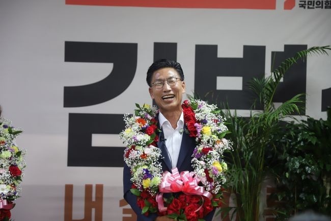 당선 소식과 함께 지지자들에게 받은 축하 꽃다발을 목어 걸고 밝게 웃고 있는 김병삼 영천시장 당선인. ⓒ 김병삼 캠프