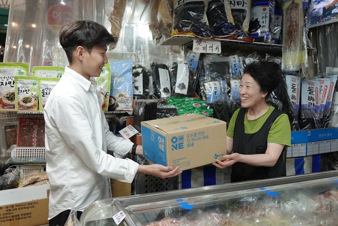 대전 태평시장 건어물가게 상인이 배송접수센터를 통해 접수할 택배 상자를 배송 매니저에게 전달하고 있다. ⓒ CJ대한통운
