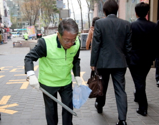 시민들이 명동 거리에서 발걸음을 재촉하며 지나가는 가운데 윤용로 외환은행장이 환경 정화 작업을 하고 있다. 23일 외환은행 임직원들은 서울 중심가인 명동에서 환경 정화 봉사를 진행했다. ⓒ 외환은행