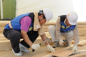  IBK투자증권 조강래 대표이사(왼쪽)가 강원 춘천시 동면의 한국해비타트 건축공사 현장에서 지붕 트러스 골조에 못을 박고 있다. ⓒ IBK투자증권