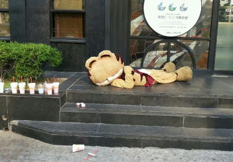  고양이 인형탈이 무더위에 지쳐 바닥에 드러누워있다. 그 옆으로 빈 음료 용기들이 줄지어 세워져있다. = 조민경 기자