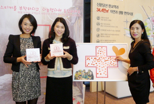  SK건설 분양관계자들이 대한적십자사 희망나눔 명패를 들어 보이며 하트스티커를 붙이고 있다. ⓒ SK건설