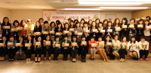  라이나생명 텔레마케터 자원봉사자들이 홀몸어르신들을 위해 직접 쓴 편지와 카네이션, 선물을 포장한 택배 박스를 들고 기념 촬영을 하고 있다. ⓒ 라이나생명