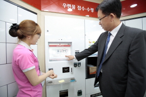  30일 창구직원이 없는 첨단 무인우체국이 김포와 하남에 국내 처음으로 개국했다. 김준호 우정사업본부장(오른쪽)이 김포이젠 무인우체국에서 소포 우편물을 접수하고 있다. ⓒ 우정사업본부