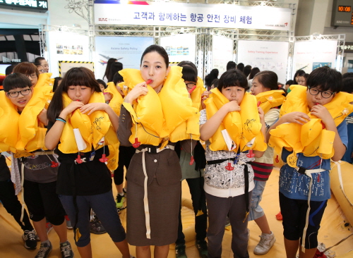  아시아나항공이 김포공항 국내선 청사에서 항공안전장비 체험행사를 가졌으며, 캐빈승무원이 김포공항을 찾은 여행객들에게 구명조끼 등 비상장치 사용법을 시연하고 있다. ⓒ 아시아나항공